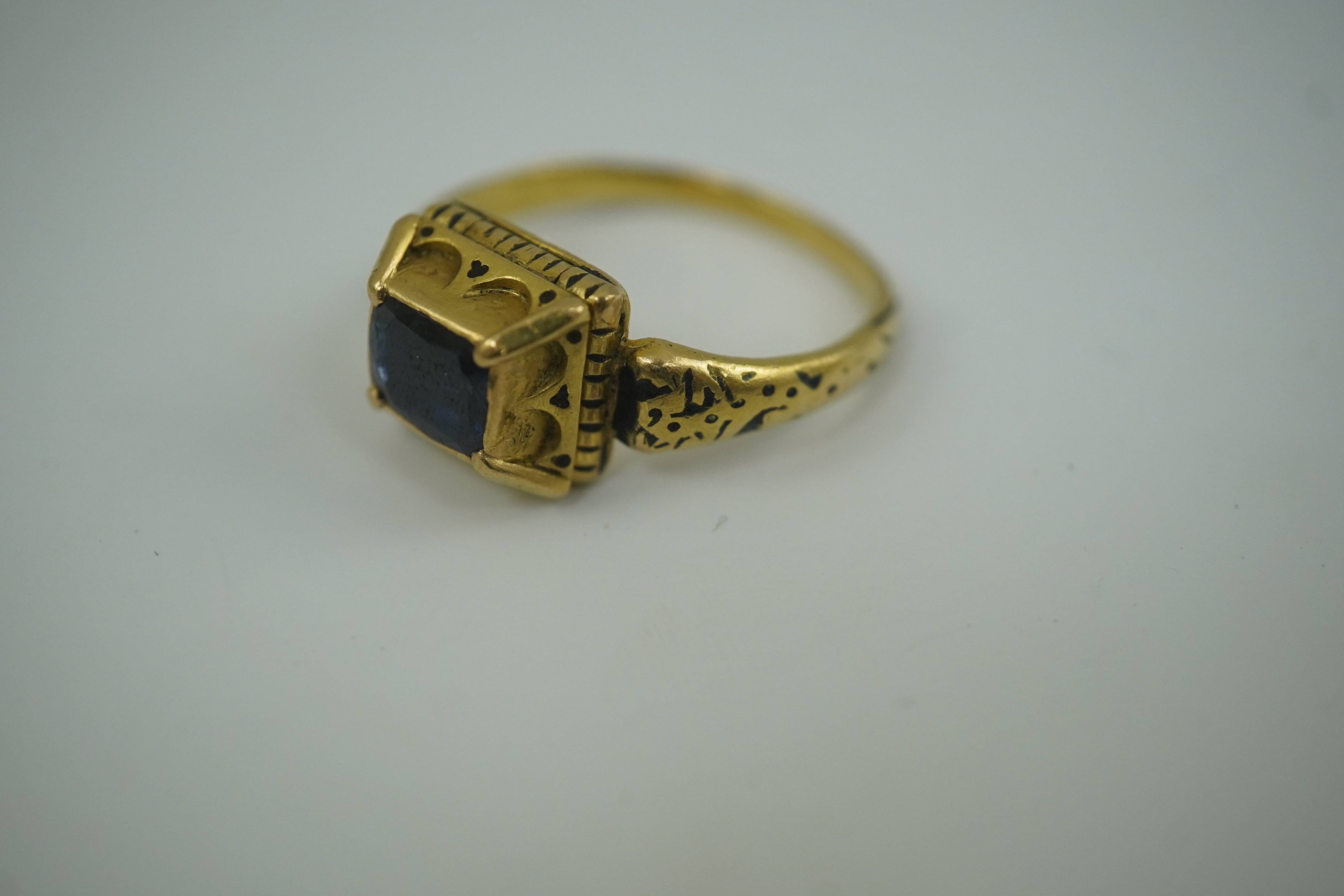 An antique high carat gold, black enamel and later? collet set cushion cut sapphire set 'poison' ring